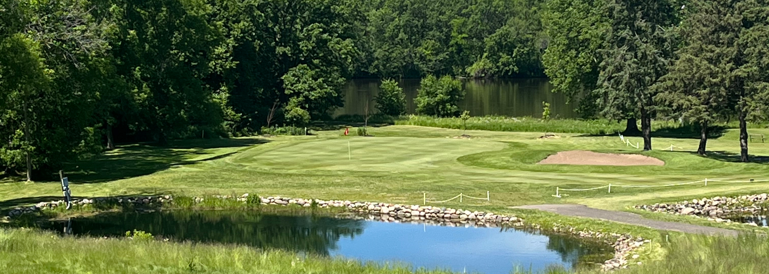 Pond on golf course with trees and cart path